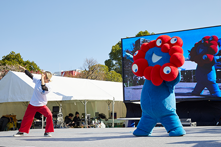 ダンスする人と、大阪関西万博公式キャラクター ミャクミャク